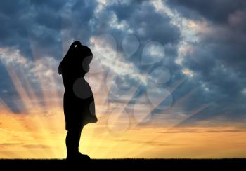Silhouette of sad little baby girl crying against sunset background. Conceptual image of child abuse