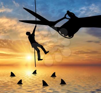 Scissors cut the rope on which hangs a businessman and underneath sharks. The concept of risk in business