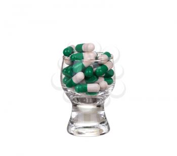 A glass of pills and capsules on white background