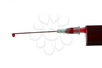 Close up image of a drop of red liquid on the needle of a syringe against a white background