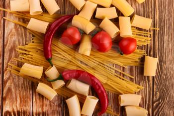 Pasta with cherry tomatoes and other ingredients on wooden table background (seen from above)