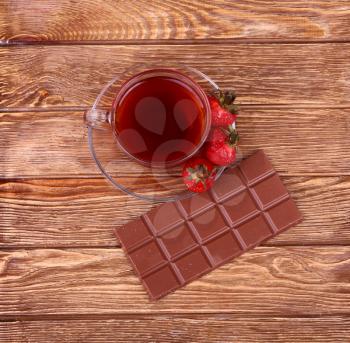 A cup of tea or coffee. Dark Chocolate. Wooden background.