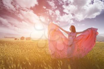 Beauty Romantic Girl Outdoors. Beautiful Teenage Model Dressed in Long Pink Dress on the Field in Sun Light. Blowing Long Hair. Autumn. Glow Sun, Sunshine. Backlit. Toned in warm colors