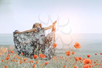 beautiful girl in a poppy field at sunset. concept of freedom