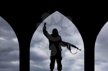 Concept of a terrorist. Silhouette terrorists with rifle at sunset