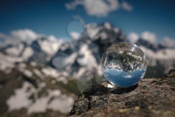 Transparent glass sphere and snow-capped peaks in the background. Concept and idea of travel