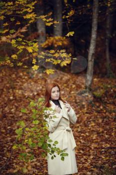 Portrait of a beautiful, dreamy and sad girl with red hair in white coat autumn.