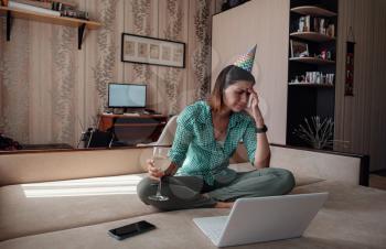Girl celebrating birthday online in quarantine time through video call virtual party. Coronavirus outbreak 2020. sad depressed woman