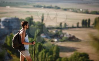 Hiking man portrait with backpack walking in nature. Caucasian man smiling happy with valley in background during summer trip.