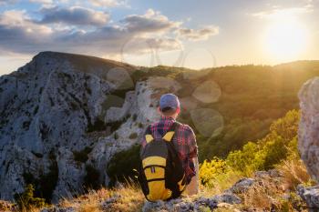 Adventurous man is on top of the mountain and enjoying the beautiful view during a vibrant sunset. success, winner, leader concept and idea