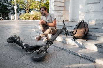 Young Man Accident With An Electric Scooter On Street. A man fell from a scooter on a city street.