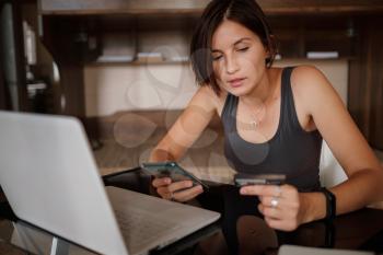 A young asian woman holds a credit card and uses a laptop. The concept of online shopping. black Friday or other sale