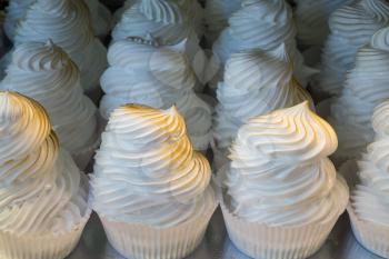 Row of baked meringues in individual paper cases in bakery in Madrid Spain