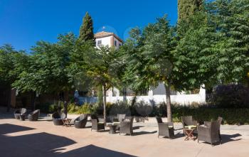 Wicker tables and chairs set out in courtyard of a boutique hotel ready for afternoon drinks