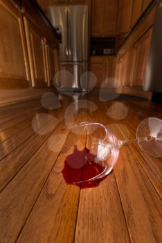 Concept of domestic disturbance at home with broken wine glass on floor of modern kitchen