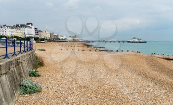 View along promenade and pebbly beach of Eastbourne towards the pier on cloudy day