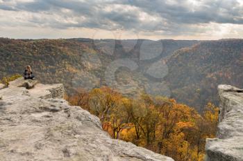 Young female woman overlooks the hills covered with fall trees from Raven Rock overlook at Coopers Rock State Forest West Virginia