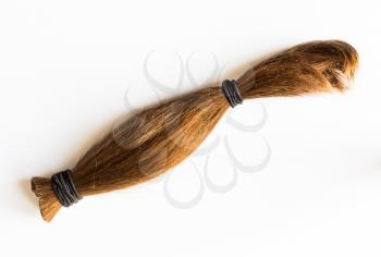Cut length of brown hair tied and ready for donation to charity for people with cancer or hair loss to make wigs and head covering