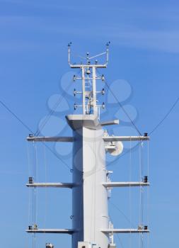 Communication tower or mast on large cruise ship with aerials and antennae against blue sky