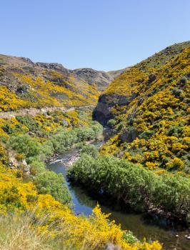 Railway track of Taieri Gorge tourist railway runs alongside river in a ravine on its journey up the valley