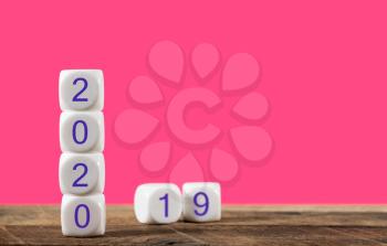 2020 spelled in blocks with 2019 in background set against living coral backdrop