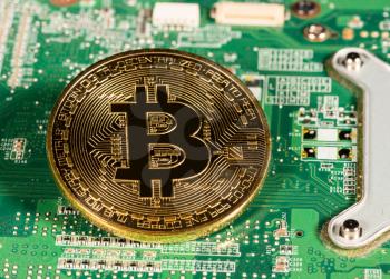 Bitcoin coin on a computer board to illustrate blockchain and cyber currency