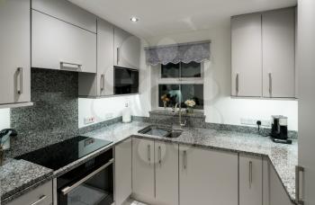 Small modern kitchen in UK apartment with granite and new appliances including induction cooktop