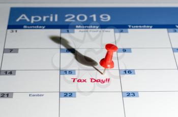 Tax day is April 15th for filing to IRS with red push pin in calendar for reminder