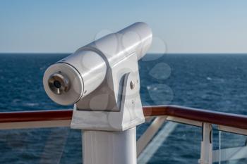 Metal optical telescope on deck of cruise boat looking at empty ocean