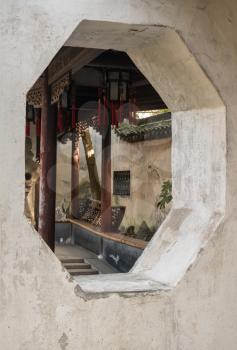 Window into small courtyard with tree planting in Yu or Yuyuan Garden in  the old city of Shanghai