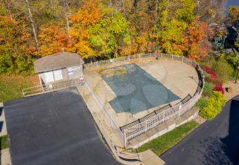 Aerial drone point of view of a green plastic cover on HOA swimming pool protecting it from leaves and for the winter storms