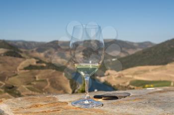 Glass of white wine for tasting above the hillsides of the Douro valley in Portugal