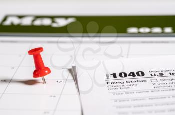 Calendar with pushpin inserted in the date for May 17 to illustrate the new tax return filing date of f17th May 2021.