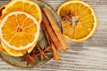 Dried orange slices, cinnamon and star anise in a plate. Spices for mulled wine on a wooden background.