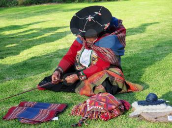 Close up of Peruvian lady in authentic dress spinning yarn by hand. (Peru)