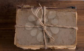 a shabby old book tied with string on a rough wooden background