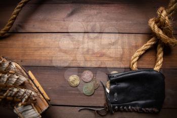Old leather pirate wallet - a bag with small copper coins lying on a dark wooden surface