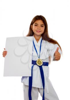 karate girl with a blue belt and a white kimono and a medal for first place holds a blank sheet of paper in her hands with a place for text.