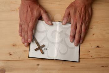 Man reading holy bible close-up on wooden background top view