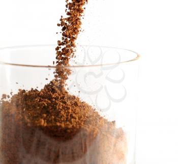 Closeup image of pouring brown instant coffee to the glass.