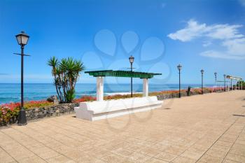 Ocean Promenade in Puerto de la Cruz, Tenerife, Spain with lamps and resting bench.