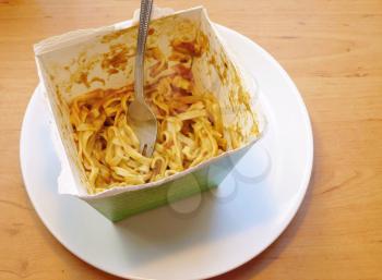 Leftover Thai noodles with green curry sauce and metal fork in paper box. Traditional noodles fast food. 