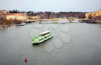 View of the Vltava river with tourist ship and Prague Castle above in old Prague town center.