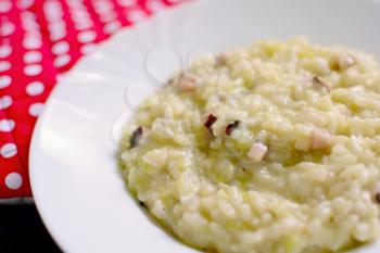 Risotto with zucchini in a white plate close up.
