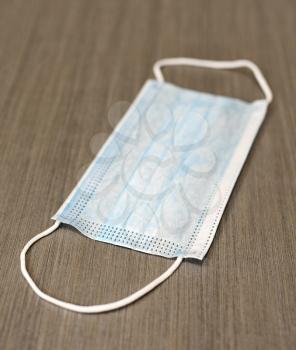 Blue surgical face mask protecting against Coronavirus Covid-19 placed on gray background.