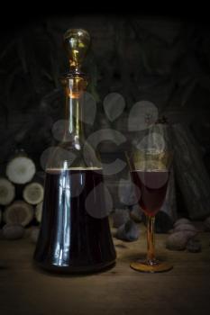 Red Wine Vintage Bottle and Glasses Resting On Wooden Table Against Christmas Background With Wood logs and Pine Branches
