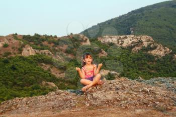 little girl sitting on a mountain top and meditate