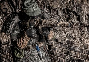 Post apocalyptic survivor, World War III soldier, global nuclear conflict partisan or stalker, in military cap and handmade body armor shooting with submachine gun wrapped in abandoned bunker or mine