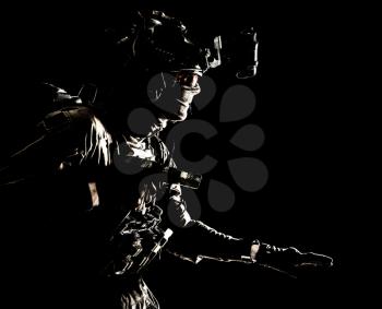 Army special operations soldier, security service fighter, commando shooter equipped modern ammunition, wearing combat helmet, mask and glasses, carefully sneaking in darkness with handgun in hand