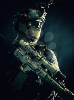 Shoulder portrait of army elite troops sniper, anti-terrorist tactical team marksman wearing helmet with thermal imager, hiding face behind mask, armed rifle with optical scope, studio shoot on black